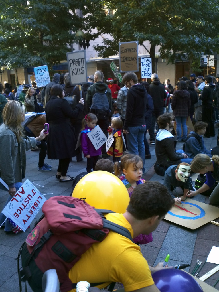 Families rally at Occupy Seattle as we prepare to march. October 15, 2013. Photo by William Bass.